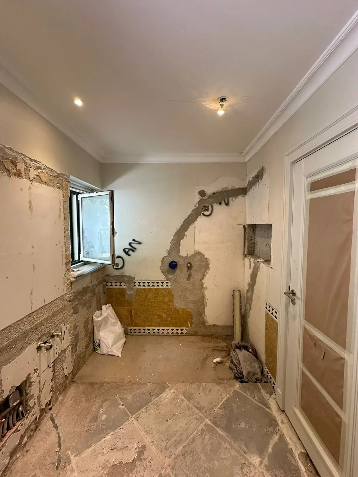 Bathroom before work, with dated ochre wall tile, chased plaster and an old stone floor