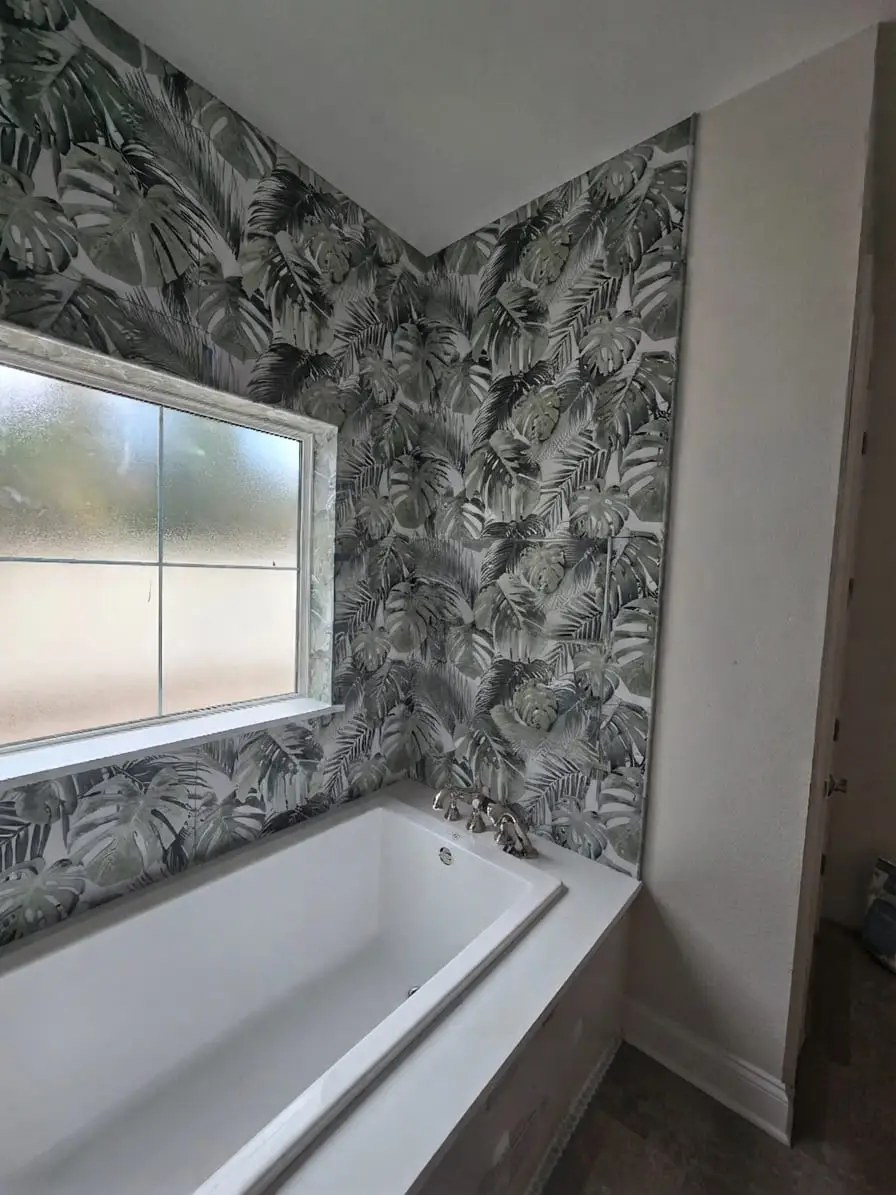 Bathtub set against a patterned botanical feature wall, with a window niche framed into the tile
