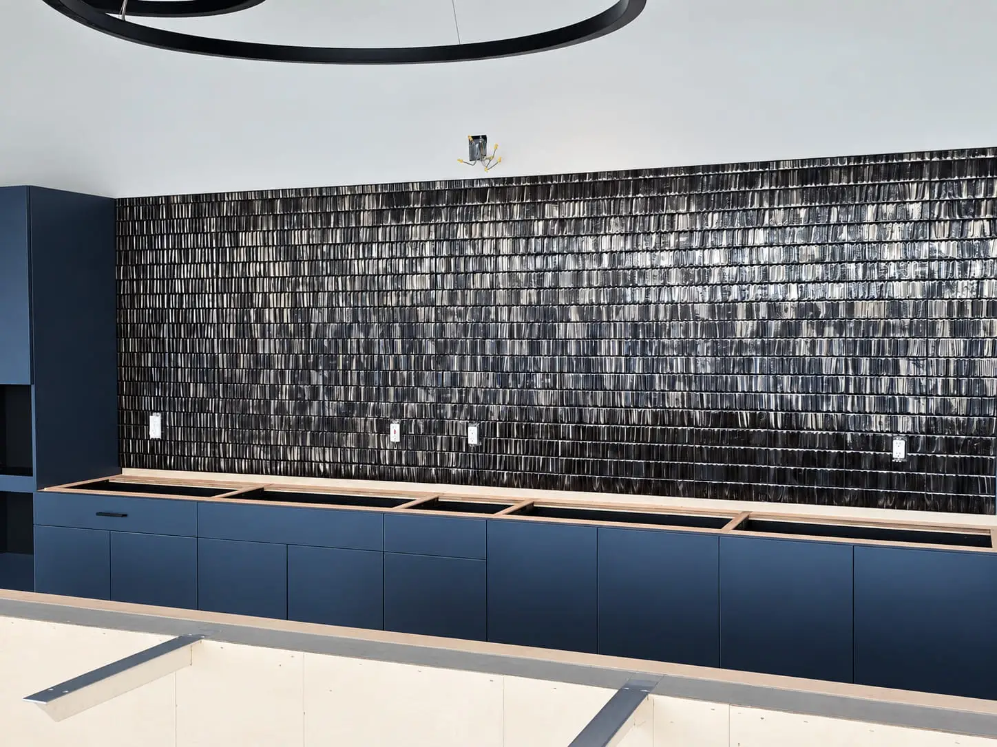 Counter wall finished in dark blue glazed tile above matching blue cabinetry