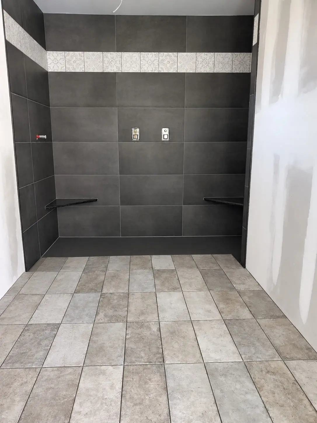Wet area in large dark porcelain wall tile with a patterned mosaic band, over a stone-look plank floor