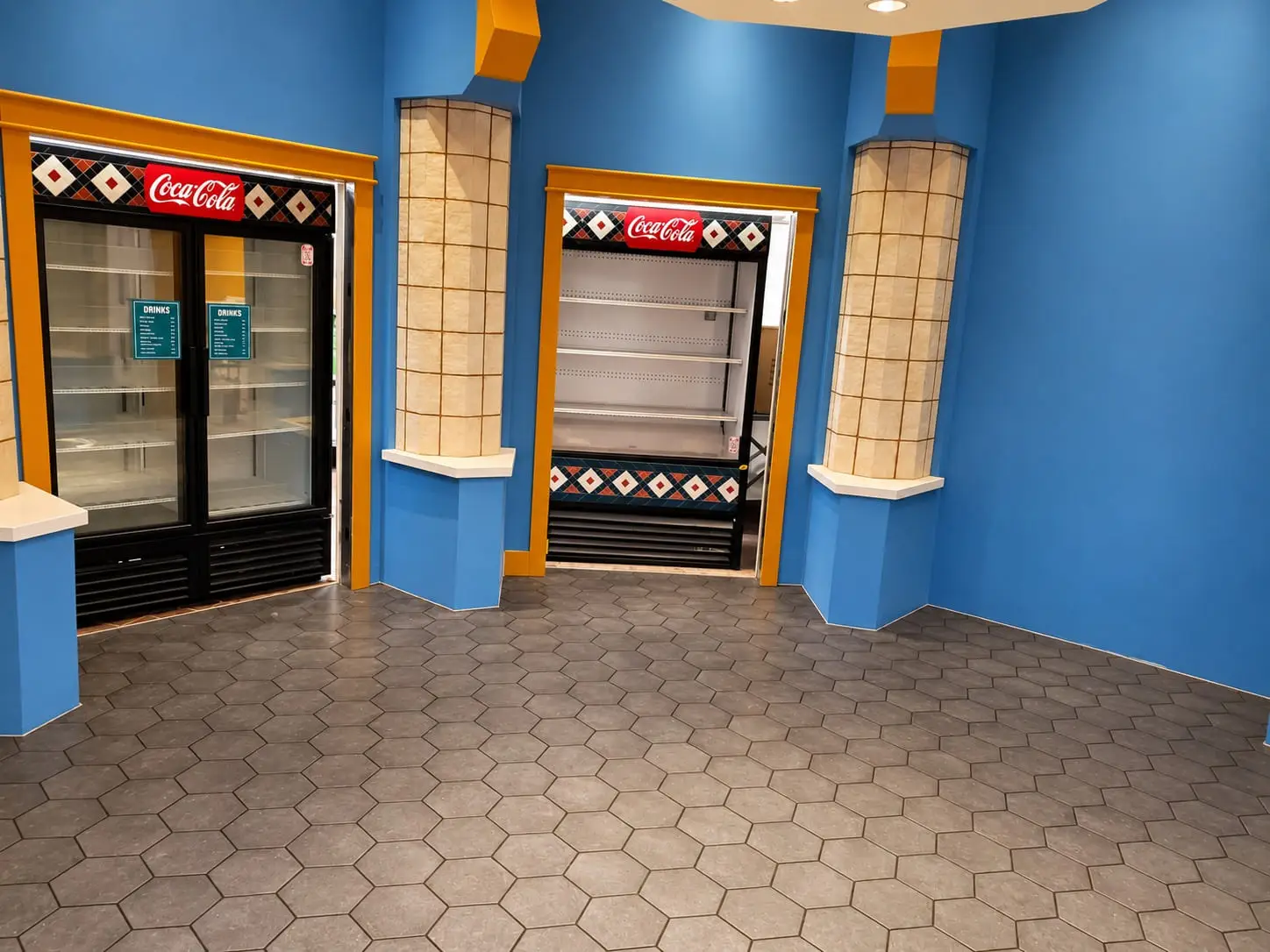Retail interior with a hexagonal porcelain floor, columns clad in glazed tile and blue feature walls around the refrigerated displays