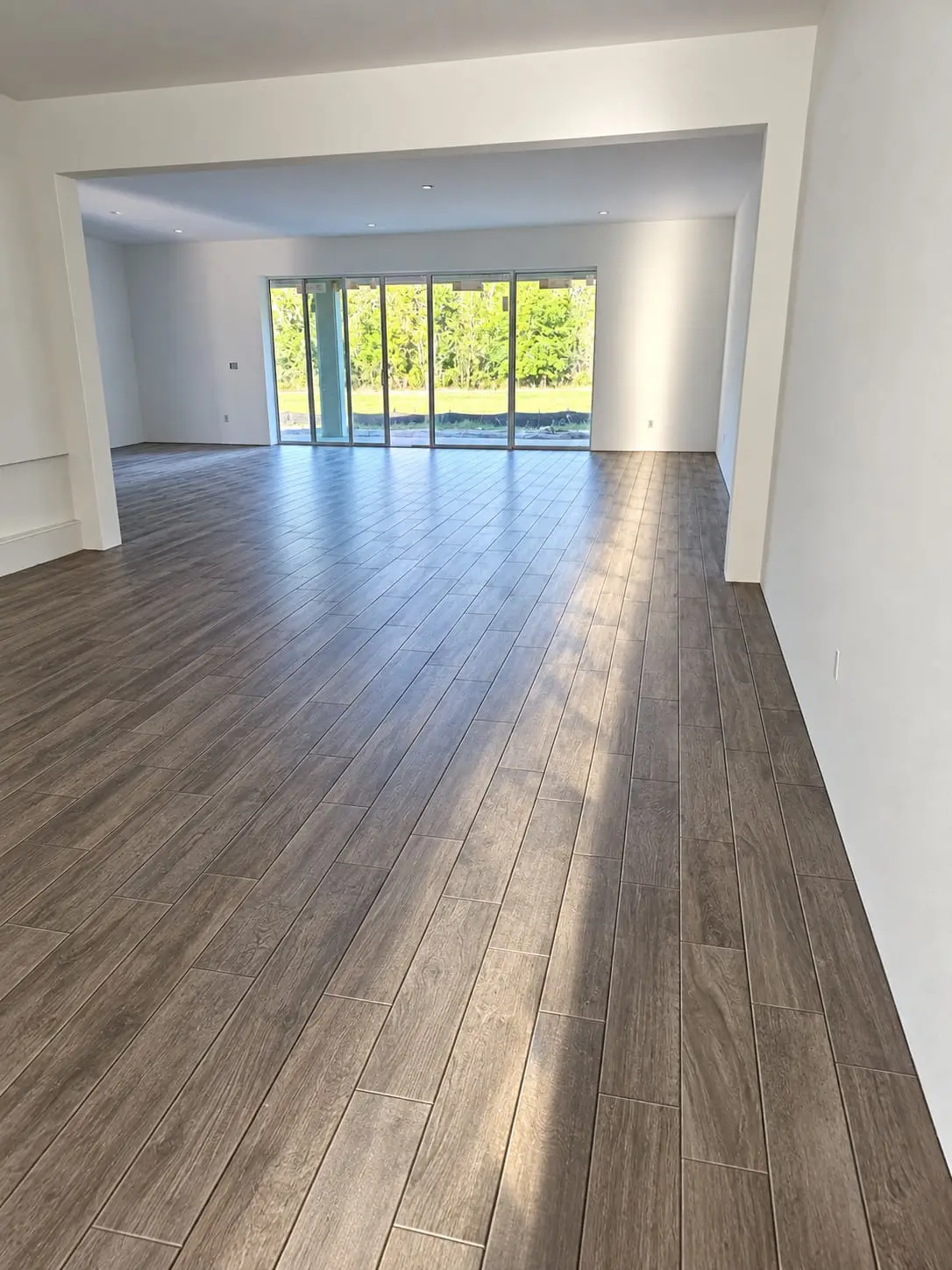 Large open room with a wood-look plank floor running in one direction toward a wall of glass doors