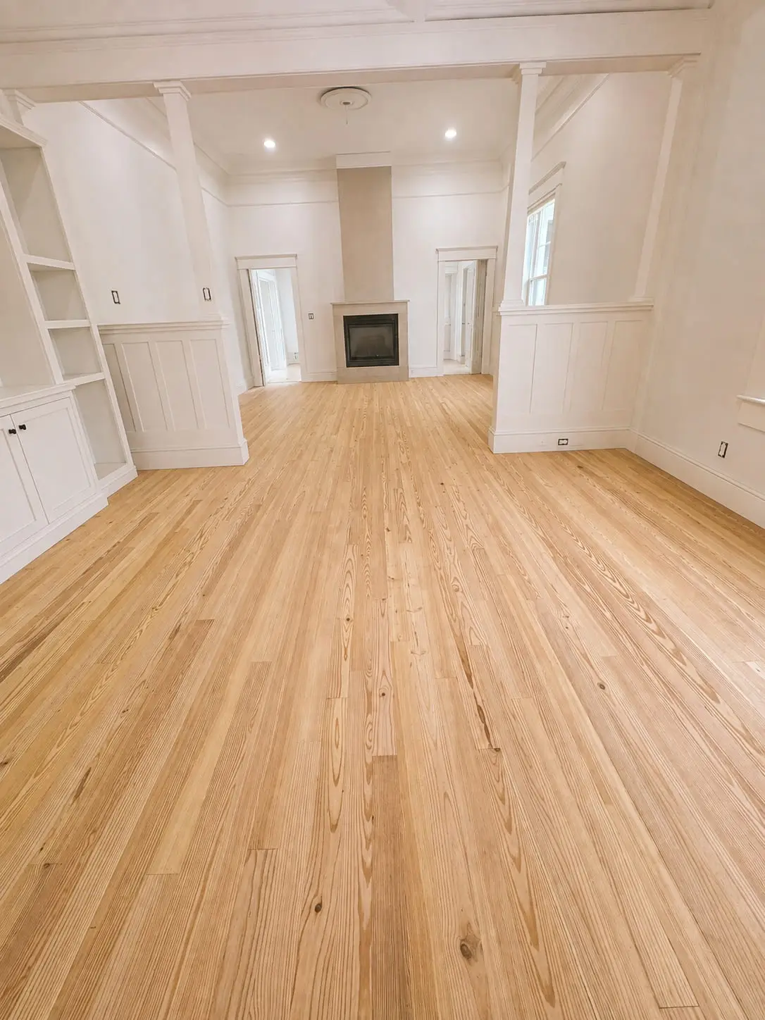 Wide-plank wood floor running the length of a living room and straight past a built-in fireplace, installed by General Tile Company
