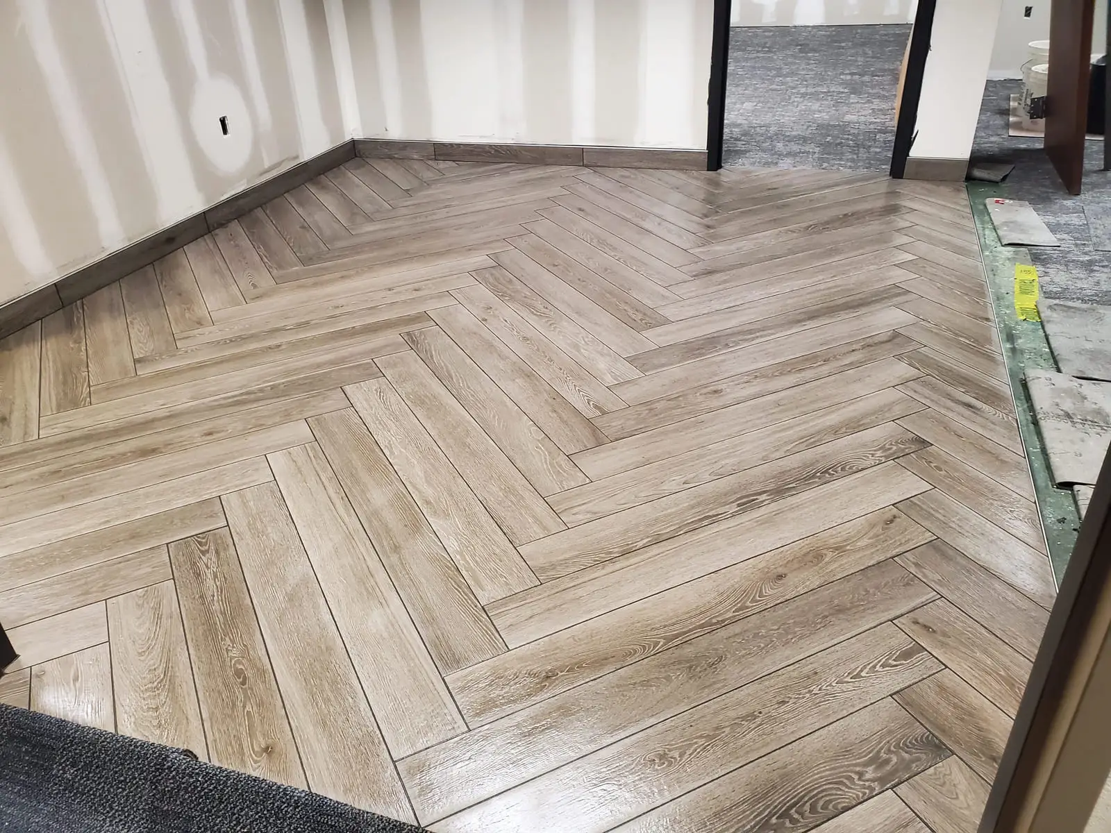 Wood-look porcelain laid in a herringbone pattern with a straight border framing the run at the perimeter
