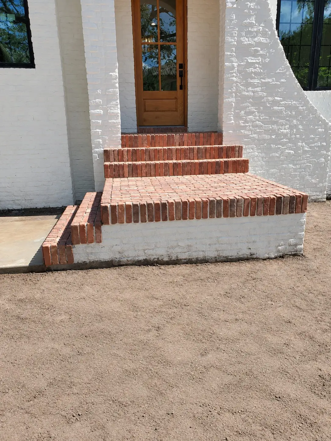 Brick front steps built up to a timber door on a white painted brick house